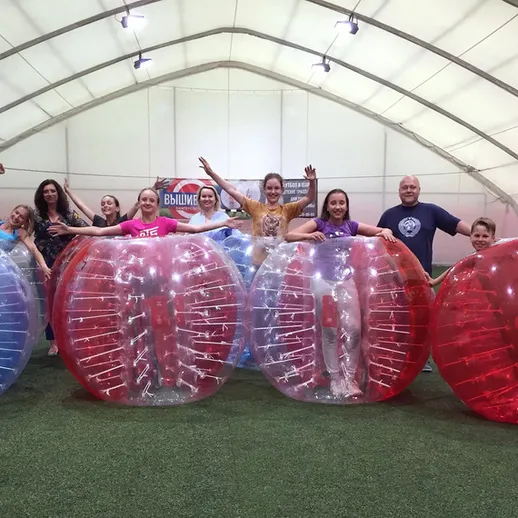 Участники спортивного мероприятия в прозрачных шарах для игры на траве в закрытом помещении