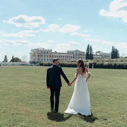 Молодожены прогуливаются по зеленому парку под ясным небом в день свадьбы