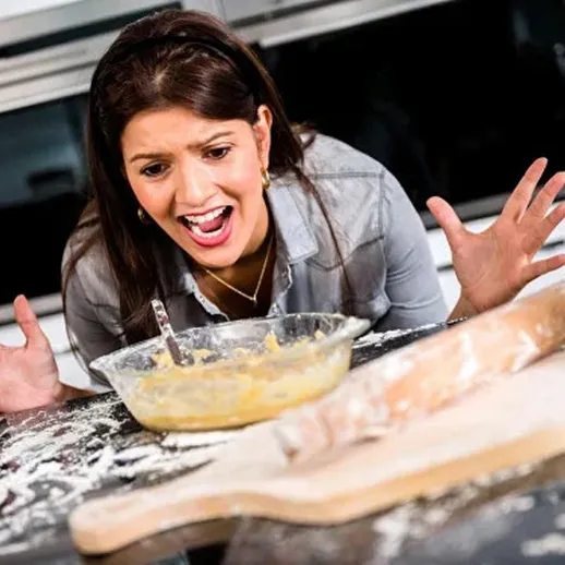 Женщина в кухне удивляется неудаче с тестом и мукой во время приготовления выпечки