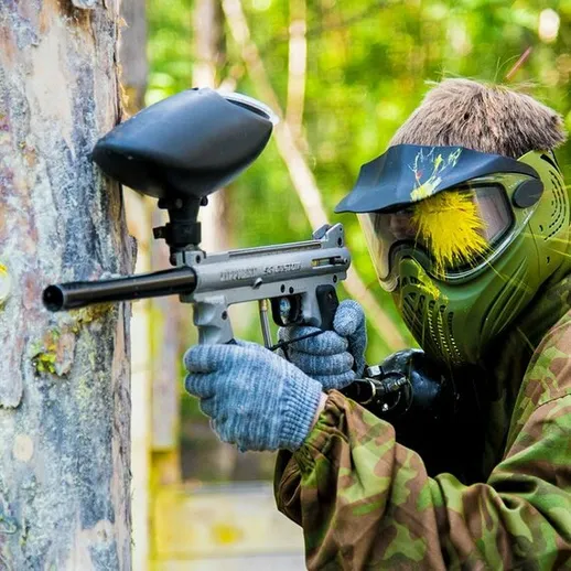 Игрок в ролевой игре в пейнтбол на открытом воздухе, прячущийся за препятствием в лесу весной