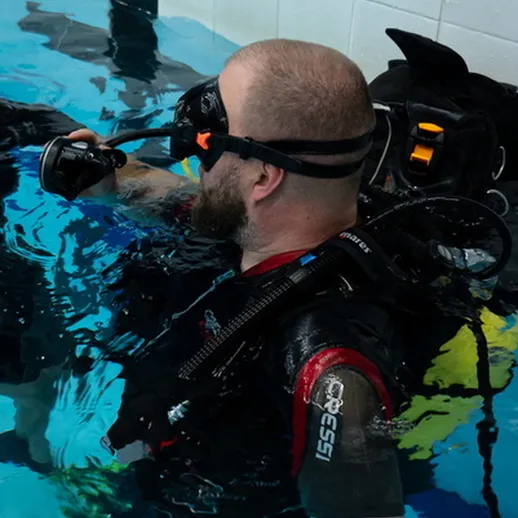 Погружение в бассейне с аквалангом под руководством инструктора во время тренировки по дайвингу