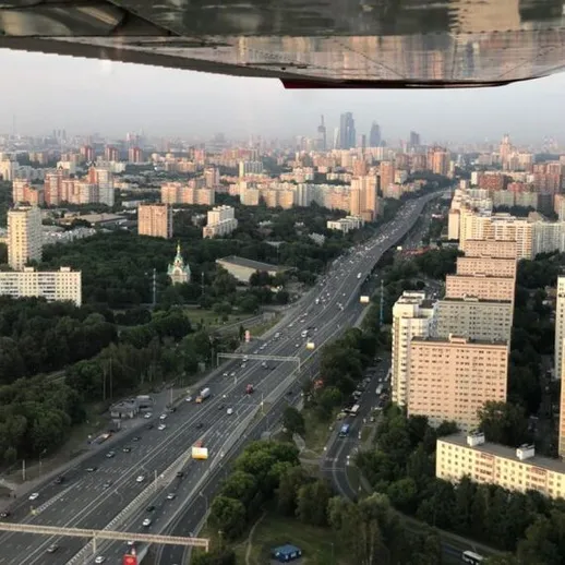 Вид на город с высоты, автомобильные дороги и жилые здания на фоне заката