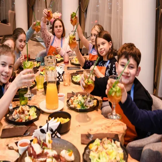 Дети празднуют день рождения в ресторане, поднимая коктейли и наслаждаясь угощениями с родителями