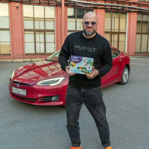 Мужчина с коробкой у красного автомобиля на парковке, солнечный день, urban стиль в городе