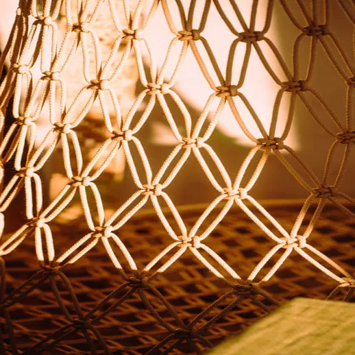 Свет, пробивающийся сквозь плетеную сетку, создает теплую атмосферу в уютном интерьере комнаты в вечернее время