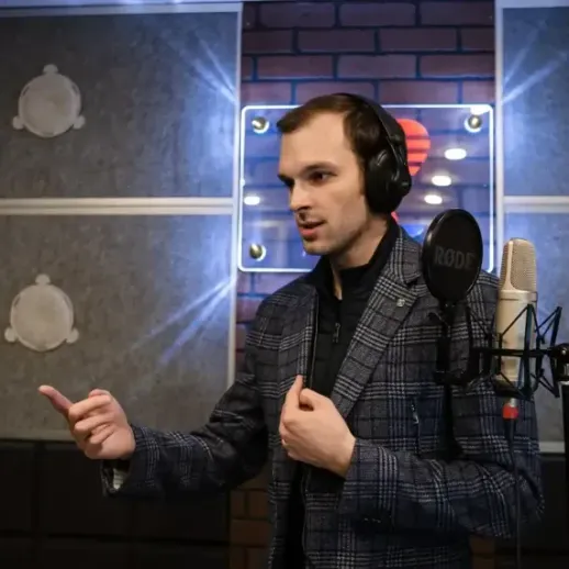 Мужчина в костюме записывает аудио в студии звукозаписи, работа над проектом в вечернее время