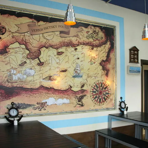 Интерьер кафе с морской картой, деревянными столами и декорациями в стиле навигации на берегу