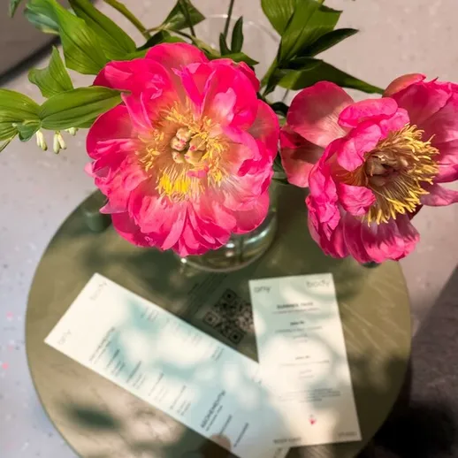 Цветы пиона в вазе на столе с меню и QR-кодом в уютном кафе