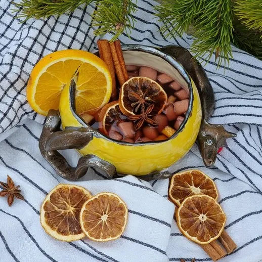 Осенний напиток в уютной кружке с лимоном и корицей на фоне текстиля