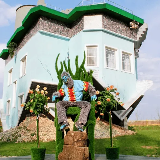 Необычный дом с ассиметричной архитектурой и зелеными растениями в спокойный солнечный день