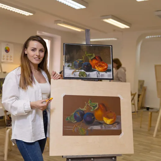 Учащаяся демонстрирует натюрморт с фруктами в художественной студии во время занятия искусством