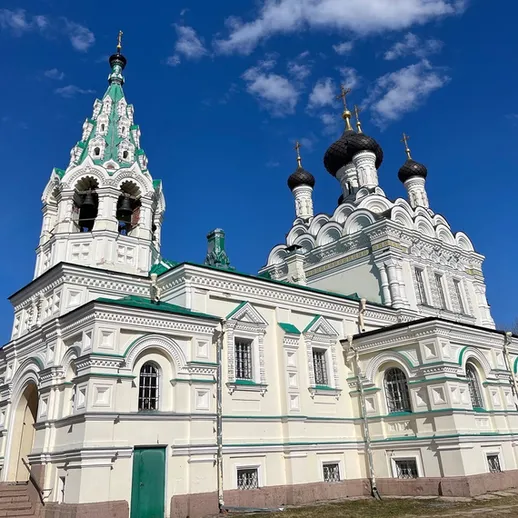 Красивая церковь с зелеными крышами на фоне голубого неба, расположенная в живописном месте