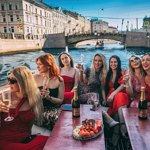 Группа девушек на прогулке на лодке по реке в Санкт-Петербурге с шампанским
