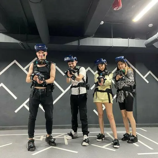 Группа людей в виртуальной реальности в игровом центре, демонстрирующих активное участие в игре с лазерными пистолетами