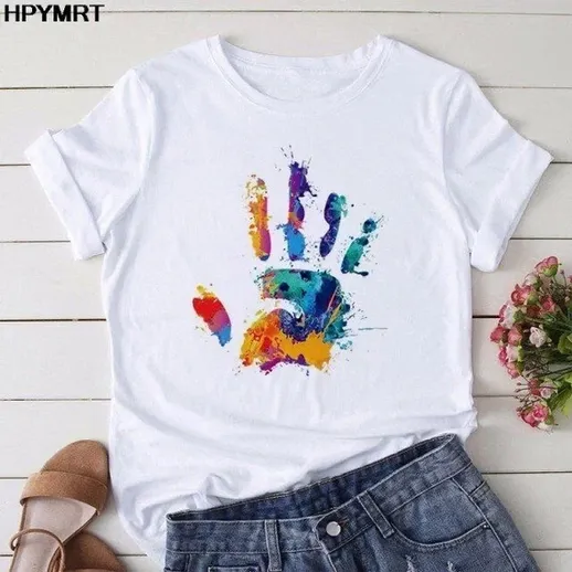 Яркая футболка с красочным отпечатком руки на фоне светлого стола и цветочного букета весной