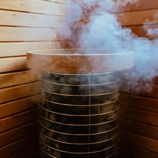 Парная с каменкой и дымом на фоне деревянных стен, создающая атмосферу уюта и расслабления в бане