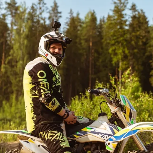 Внедорожный мотоциклист на трассе в лесу во время солнечного дня