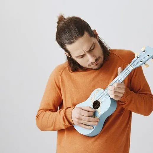 Мужчина с укулеле на белом фоне играет любимую композицию