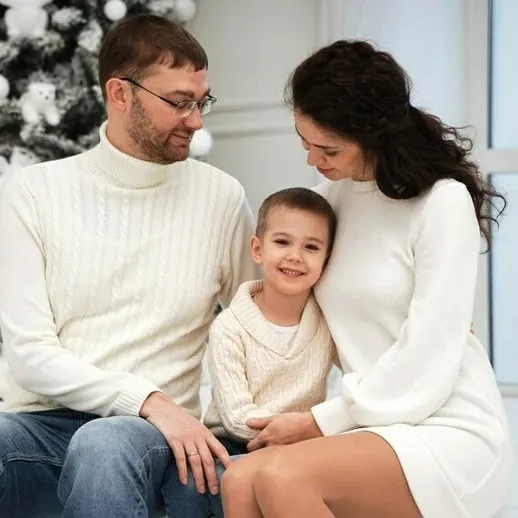 Счастливая семья сидит вместе в уютной комнате рядом с рождественской елкой в зимний день