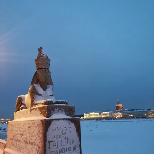 Снежный сфинкс на набережной Санкт-Петербурга в зимний вечер с огнями вдалеке