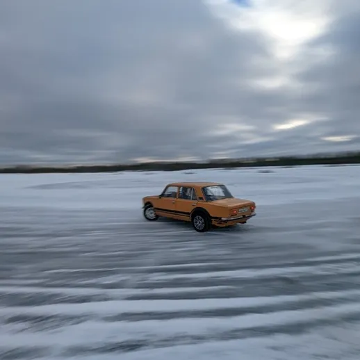 Желтый автомобиль скользит по ледяному озеру в зимний день на фоне облачного неба