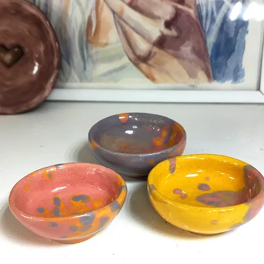 Маленькие керамические миски ручной работы на столе с акварельным рисунком на заднем плане