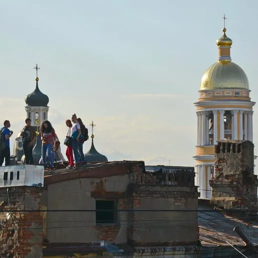 Люди на крыше старого здания в городе с куполами церквей на фоне ясного неба