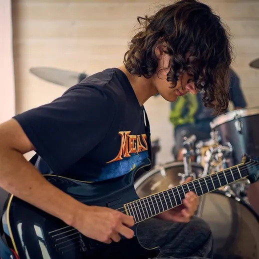 Молодой музыкант играет на электрогитаре в студии звукозаписи