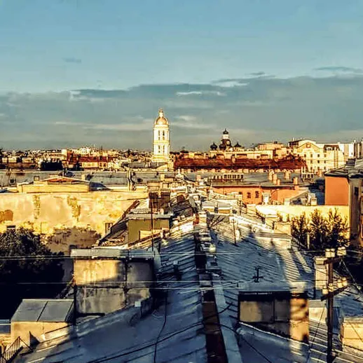 Светлый вечер в городском пейзаже с крышами домов и храмами на фоне заката