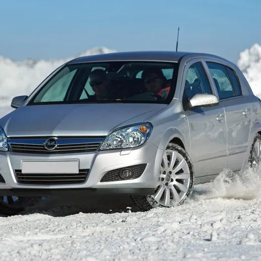 Автомобиль на снежном склоне зимой: сцена с легковым автомобилем, который проезжает по глубкому снегу