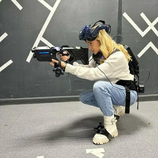 Молодая женщина в виртуальной реальности стреляет из арбалета в специализированном тире