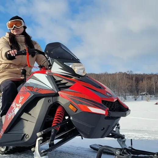 Катающаяся на снегоходе девушка на заснеженной территории в ясный зимний день