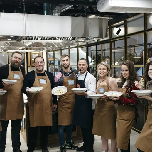 Группа людей в кулинарной школе показывает свои блюда во время кулинарного мастер-класса в Москве