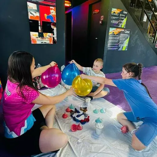 Дети и взрослые занимаются творчеством с разноцветными шарами на мероприятии в помещении