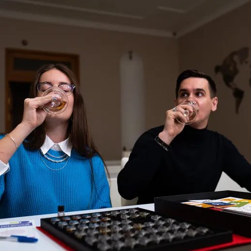 Молодая пара наслаждается напитками во время настольной игры в уютной комнате