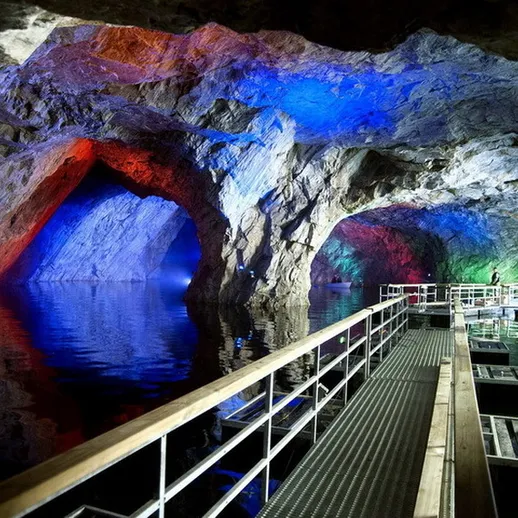 Красивые цветные скалы в подземном озере, освещенные разными цветами в пределах горной пещеры