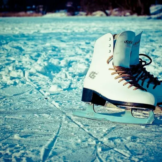 Коньки стоят на замерзшем озере, окруженном снежными берегами, в яркий зимний день