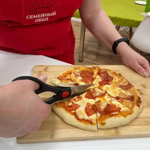 Нарезка пиццы с мясом в домашних условиях во время семейного обеда
