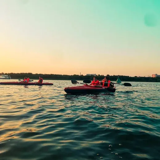 Люди катаются на каяках на спокойной воде во время заката на реке летом