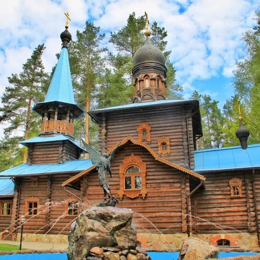 В красивом лесу стоит деревянная церковь с уникальной архитектурой и голубой крышей