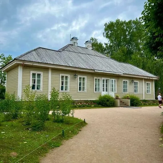 Исторический дом в парке, окружённый зеленью, с ясным небом над головой