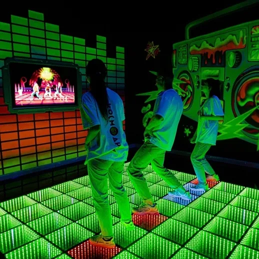 Молодежь танцует в клубе с неоновыми огнями и интерактивным экраном в вечернее время