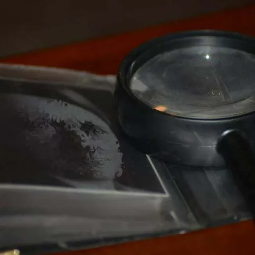 Увеличительное стекло на старом черно-белом портрете в тёмной комнате в конце дня