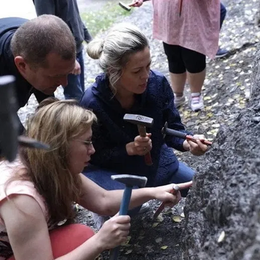 Группа людей изучает геологические слои на выезде из города, проводя исследование в осенний день