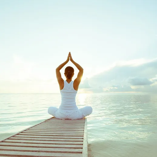 Женщина выполняет йогу на причале у моря на рассвете, наслаждаясь спокойствием и гармонией с природой