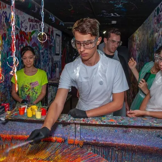 Молодежь занимается творческой деятельностью в арт-пространстве с краской и всплесками красок в душном помещении