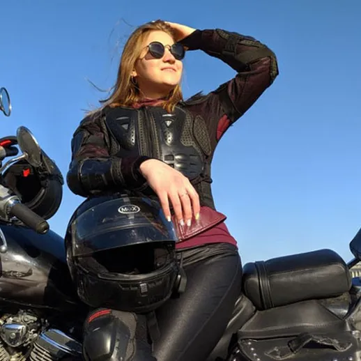 Молодая женщина в солнцезащитных очках позирует с мотоциклом на набережной в солнечный день