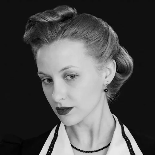 Модная женщина с винтажной прической на черном фоне во время фотосессии в ретро-стиле