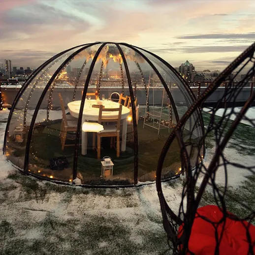 Уютный зимний ужин в стеклянном куполе на крыше с видом на город
