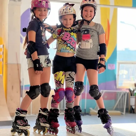 Три девочки на роликах в скейтпарке, наслаждающиеся активным отдыхом и трюками в летний день